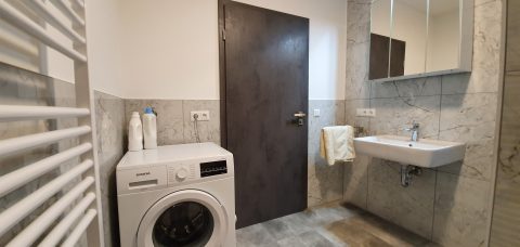 Wohnung Lena: Badezimmer mit Waschbecken, Waschmaschine und Handtuchheizkörper